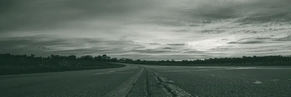 A two-lane highway at dusk, seen from the center line