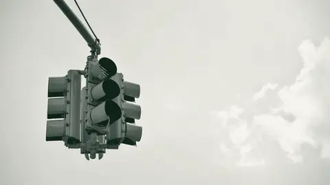 A traffic signal showing red against a pale sky